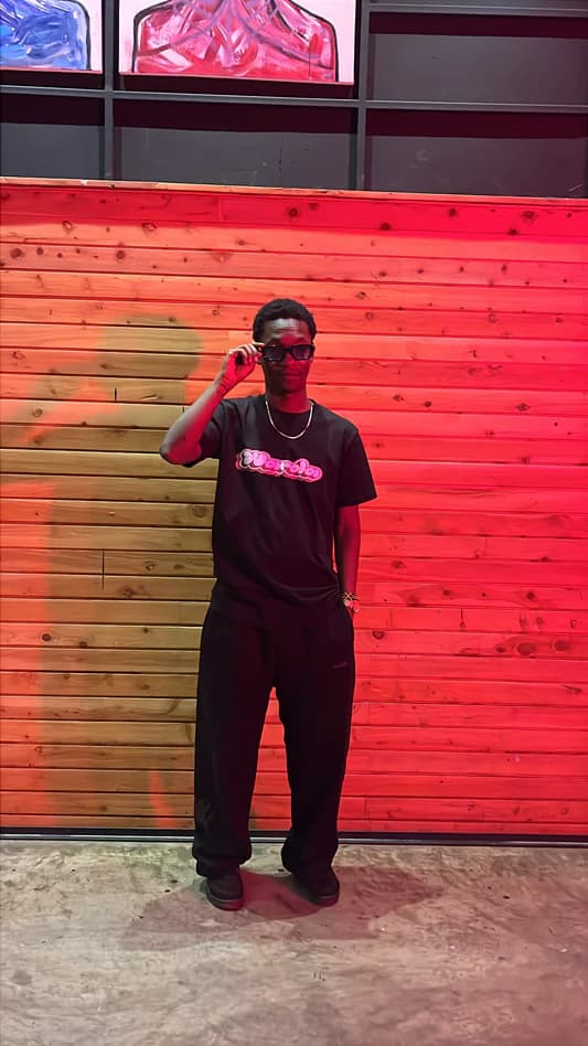 WARDA wearing his own pink-bubble wordmark tee at his creative space in Nairobi
