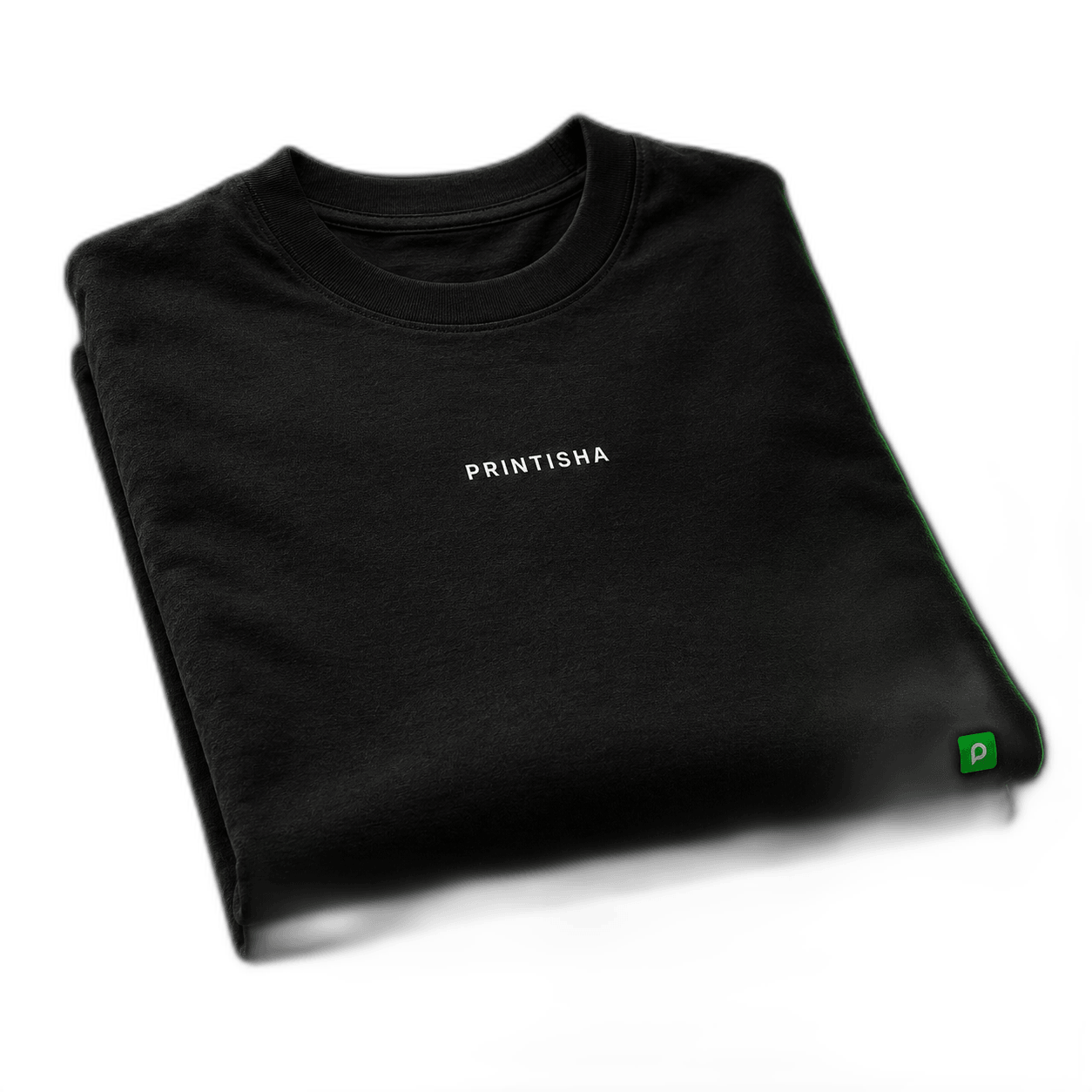 A folded premium black premium t-shirt with the PRINTISHA wordmark on the chest and a small green Printisha P-tile mark on the hem