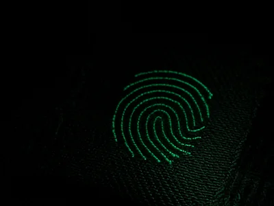 A green fingerprint-ridge emblem glowing on dark fabric
