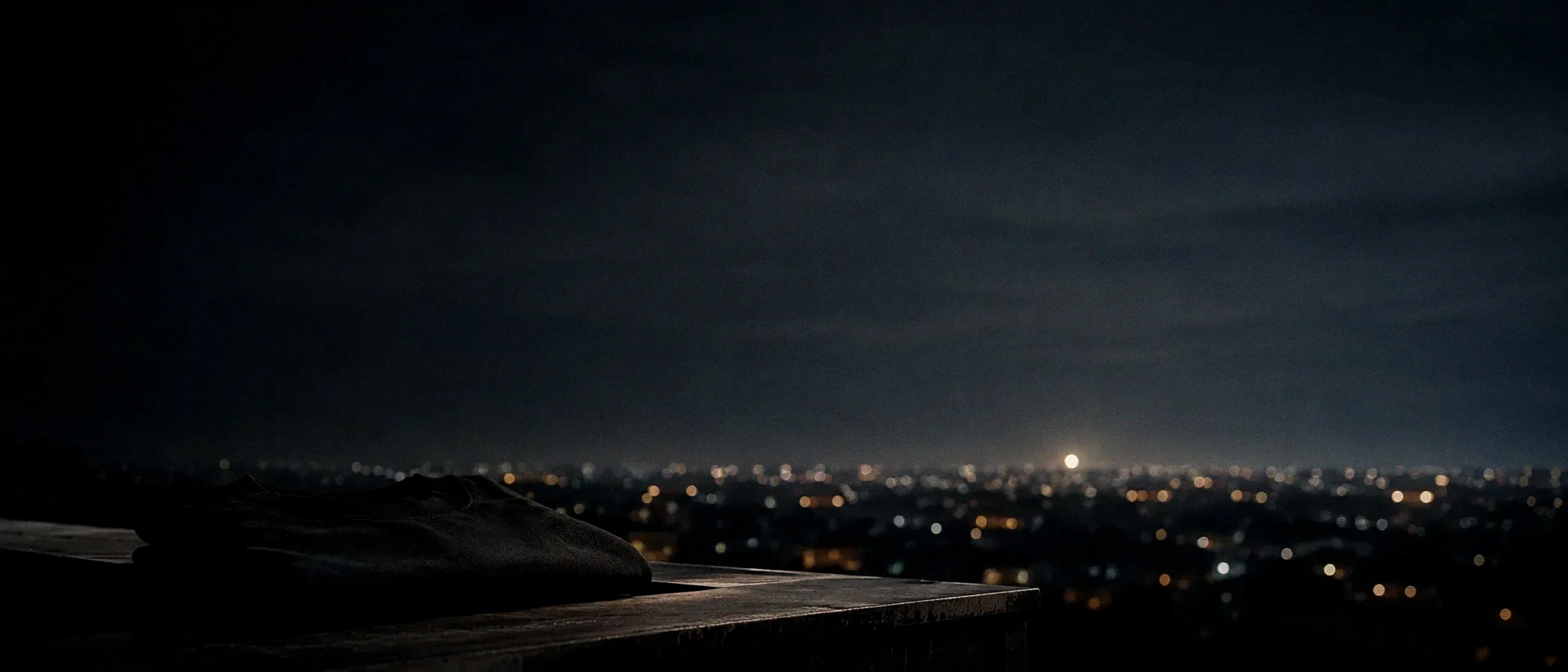 A folded garment resting on a rooftop ledge at 23:30, Nairobi's lights spread below